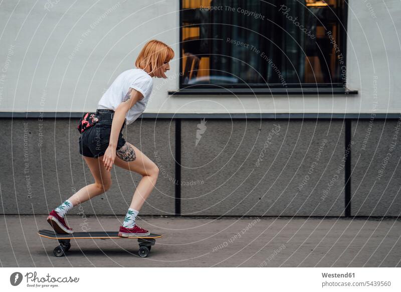 Junge Frau fährt Carver Skateboard auf dem Bürgersteig Gehsteig Gehwege Gehsteige Bürgersteige Straßenpflaster Trottoir fahren weiblich Frauen Rollbretter