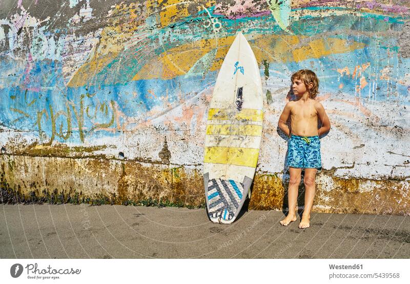 Chile, Pichilemu, Junge stehend an einer bunten Wand mit Surfbrett farbig mehrfarbig Surfbretter surfboard surfboards Mauer Mauern steht Buben Knabe Jungen