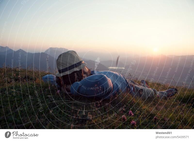 Österreich, Tirol, Unterberghorn, Mann entspannt sich bei Sonnenuntergang auf Almwiese Freizeitaktivität ländliches Motiv nicht städtisch Bergwandern