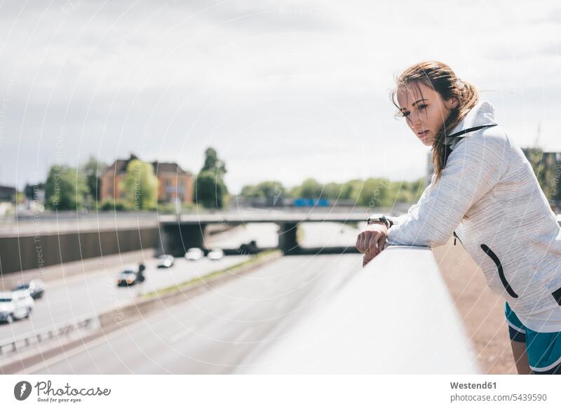 Sportliche junge Frau lehnt an Geländer an der Autobahn aufstützen aufgestuetzt aufgestützt Autobahnen sportlich weiblich Frauen Straße Strassen Straßen