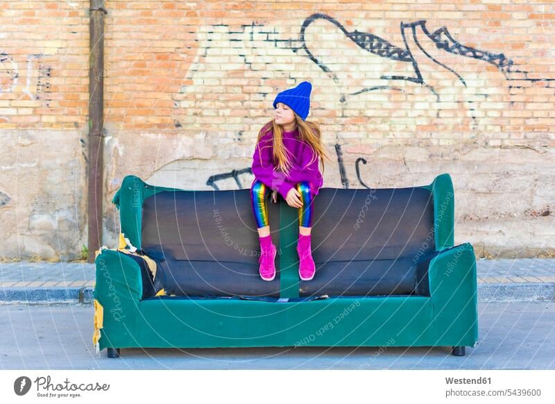Mädchen trägt bunte Kleidung und sitzt auf einer Couch im Freien Europäer Kaukasier Europäisch kaukasisch nur ein Mädchen 1 Mädchen nur ein Maedchen