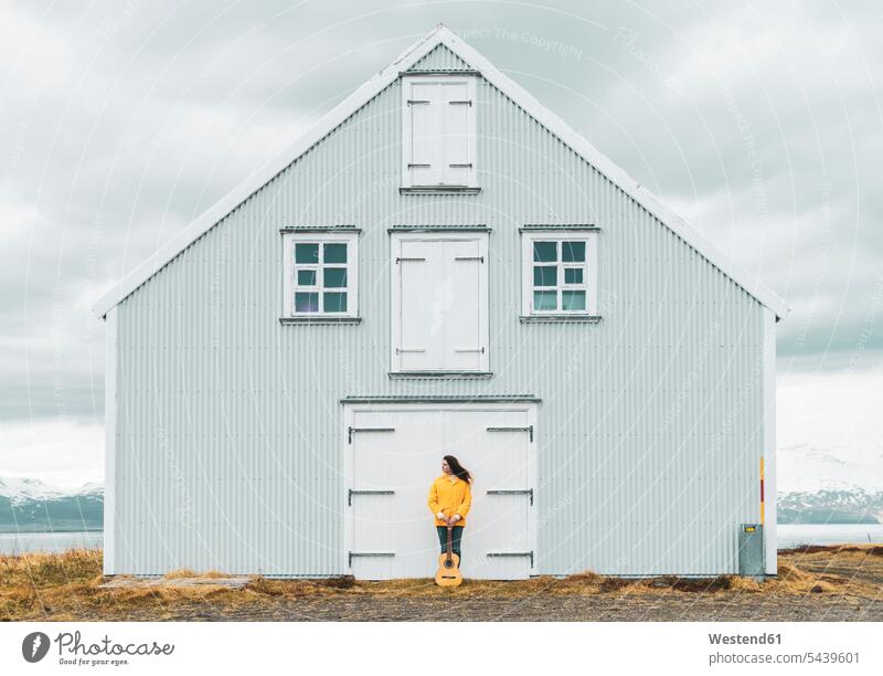 Island, Frau mit Gitarre steht an einsamem Haus Republik Island stehen stehend weiblich Frauen Häuser Haeuser einsamer einsames Gitarren Erwachsener erwachsen