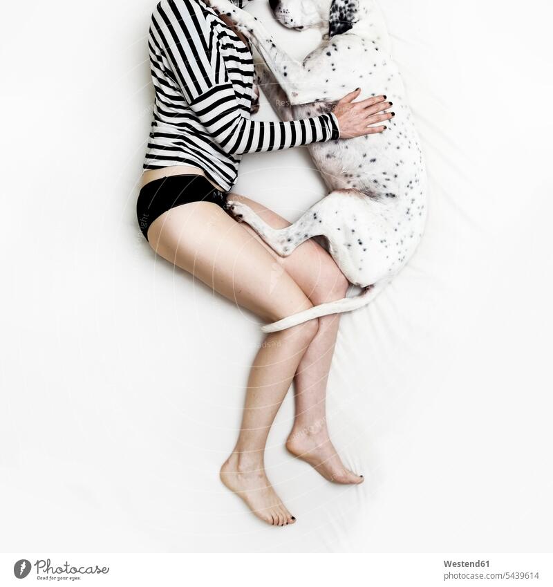 Frau und dalmatinischer Mischling liegen auf weißem Bettlaken Freizeitkleidung Freizeitbekleidung casual Mischlingshund Mischlinge Mischlingshunde Slip