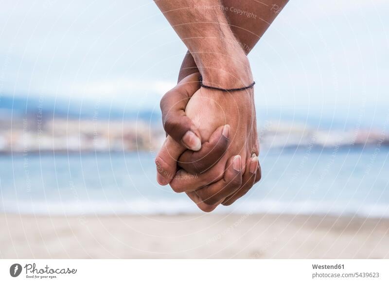 Nahaufnahme von zwei am Strand verbundenen Händen Paar Pärchen Paare Partnerschaft Beach Straende Strände Beaches Gemeinsam Zusammen Miteinander Hand Liebe