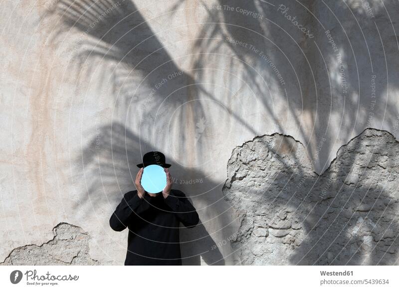 Marokko, Essaouira, Mann mit Bowlerhut hält Spiegel vor sein Gesicht an einer Wand Männer männlich halten Melone Bowler Hat Erwachsener erwachsen Mensch