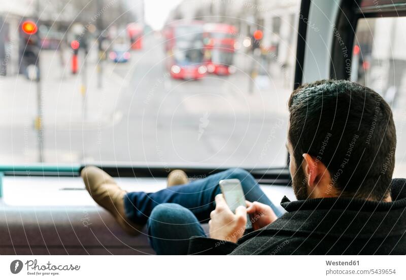 Großbritannien, London, junger Mann in einem Doppeldeckerbus mit seinem Smartphone Europäer Kaukasier Europäisch kaukasisch unterwegs auf Achse in Bewegung