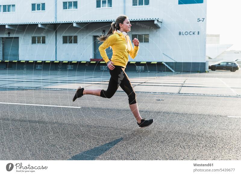 Junge Frau rennt auf einer Straße weiblich Frauen laufen rennen Joggen Jogging Strassen Straßen Erwachsener erwachsen Mensch Menschen Leute People Personen