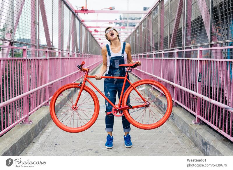 USA, New York City, Williamsburg, Frau mit rotem Rennrad auf der Williamsburg Bridge Europäer Kaukasier Europäisch kaukasisch Kopf nach hinten eine Person