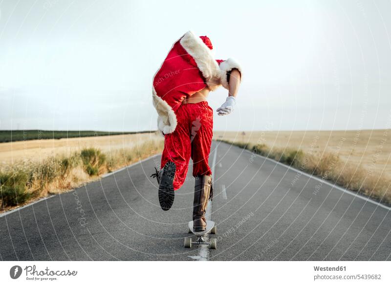 Der Weihnachtsmann fährt auf Longboard auf der Landstraße Leute Menschen People Person Personen Europäisch Kaukasier kaukasisch 1 Ein ein Mensch eine