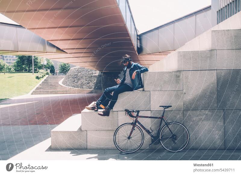Spanien, Bilbao, Mann mit Smartphone und Kopfhörer, Rennrad Europäer Kaukasier Europäisch kaukasisch Außenaufnahme draußen im Freien Musik Hipster Kopfhoerer