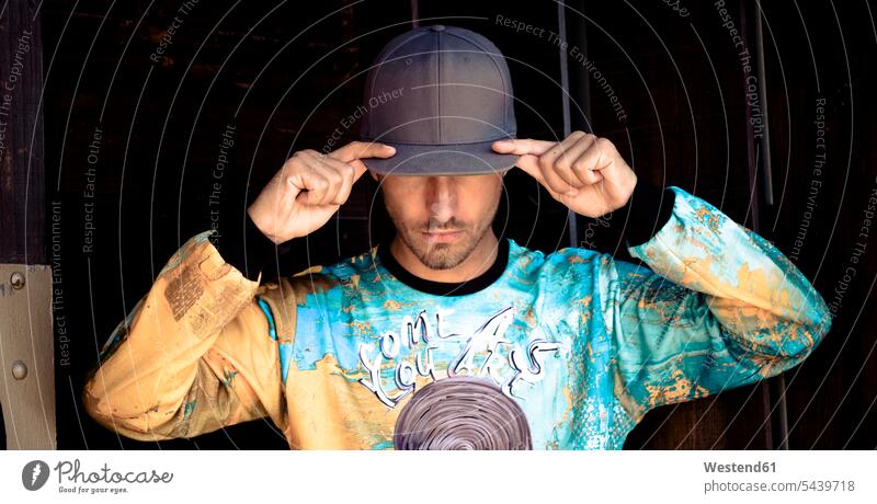 Stilvoller junger Mann mit Basecap und bedrucktem Hemd Männer männlich Schirmmuetze Mütze Schirmmütze Muetze Kopfbedeckung Shirt Style stylisch Aufdruck