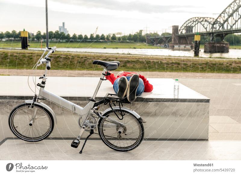 Ältere Frau mit Stadtfahrrad macht auf Bahnsteig liegend eine Pause weiblich Frauen Fahrrad Bikes Fahrräder Räder Rad Erwachsener erwachsen Mensch Menschen