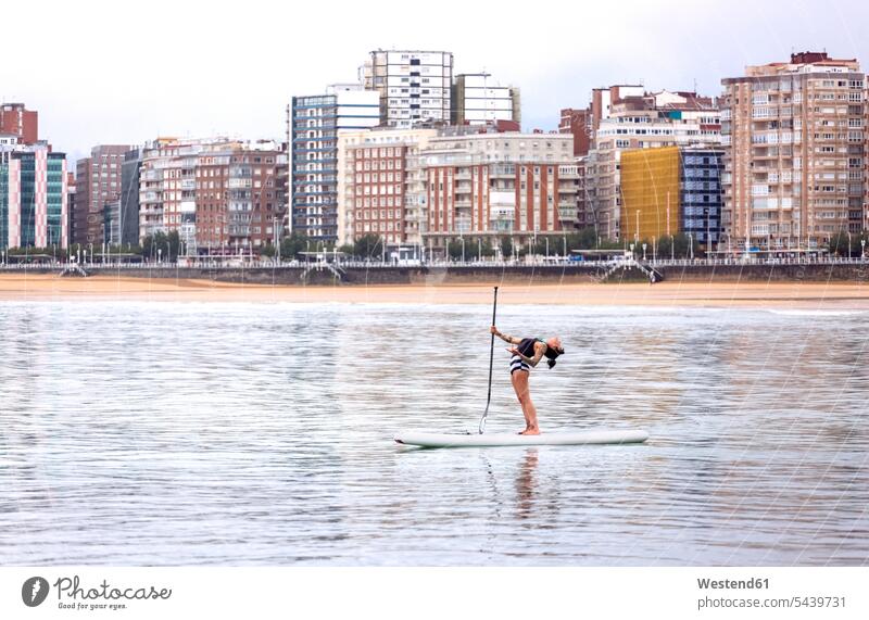 Spanien, Gijon, Frau, die Paddelbrett-Yoga praktiziert Surfbrett Surfbretter surfboard surfboards Yoga-Übungen Yogauebungen Yogaübungen Jogauebung Jogauebungen