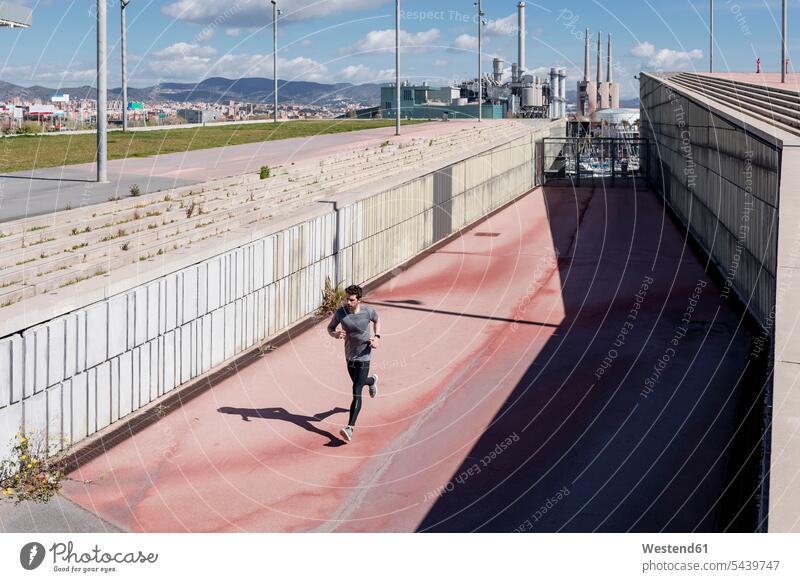 Sportlicher Mann rennt gegen eine Mauer in der Stadt sportlich Männer männlich laufen rennen Mauern staedtisch städtisch Erwachsener erwachsen Mensch Menschen