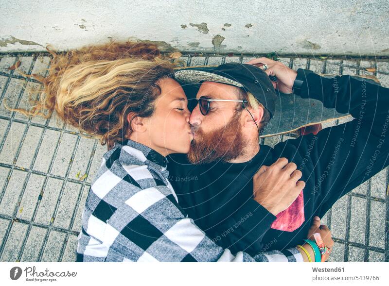 Auf dem Skateboard liegendes Paar küsst sich liegt Liebe lieben küssen Küsse Kuss Pärchen Paare Partnerschaft positiv Emotion Gefühl Empfindung Emotionen