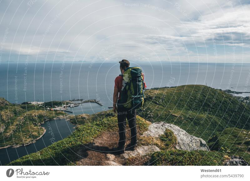 Norwegen,,, Lofoten, Moskenesoy, Backpacker auf Klippe stehend, Blick auf den Atlantik Atlantischer Ozean Königreich Norwegen steht Rucksacktourist Abhang