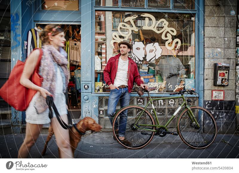 Deutschland, Hamburg, St. Pauli, Mann mit Fahrrad wartet vor dem Oldtimerladen, Frau mit Hund kommt heraus Paar Pärchen Paare Partnerschaft Geschäft Shop Laden