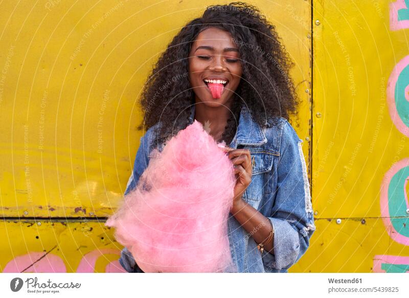 Porträt einer lächelnden jungen Frau mit herausgestreckter Zunge aus rosa Zuckerwatte Leute Menschen People Person Personen Afrikanisch Afrikanische Abstammung