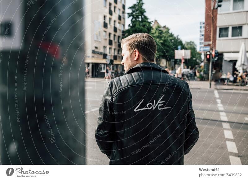 Rückenansicht eines jungen Mannes in schwarzer Lederjacke mit Schriftzug "Love" Lederjacken Liebe lieben Männer männlich schwarzen schwarzes Jacke Jacken