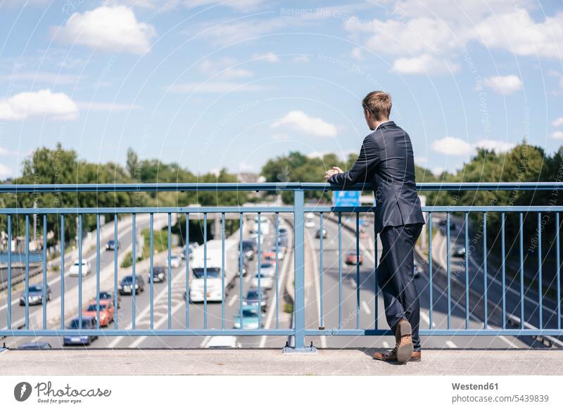 Geschäftsmann steht auf einer Brücke über eine Autobahn stehen stehend Wagen PKWs Automobil Autos Businessmann Businessmänner Geschäftsmänner Verkehr