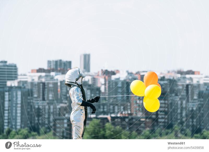 Als Astronaut verkleideter Junge hält Ballons in der Stadt Leute Menschen People Person Personen Held Raumfahrer Weltraumfahrer Astronauten Deko Dekorationen