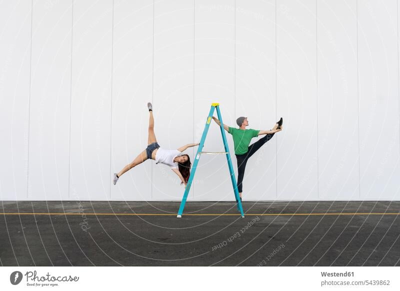 Zwei Akrobaten machen Tricks auf einer Leiter Akrobatin Paar balancieren spielen Trainieren Artistin Mensch Balance unkonventionell Gemeinsamkeit Präzision