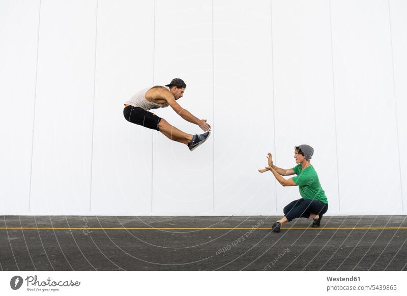 Zwei Akrobaten machen gemeinsam Kunststücke, springen in der Luft hüpfen Trainieren Übung Üben Übungen Sprung Spruenge Sprünge Kalifornien California
