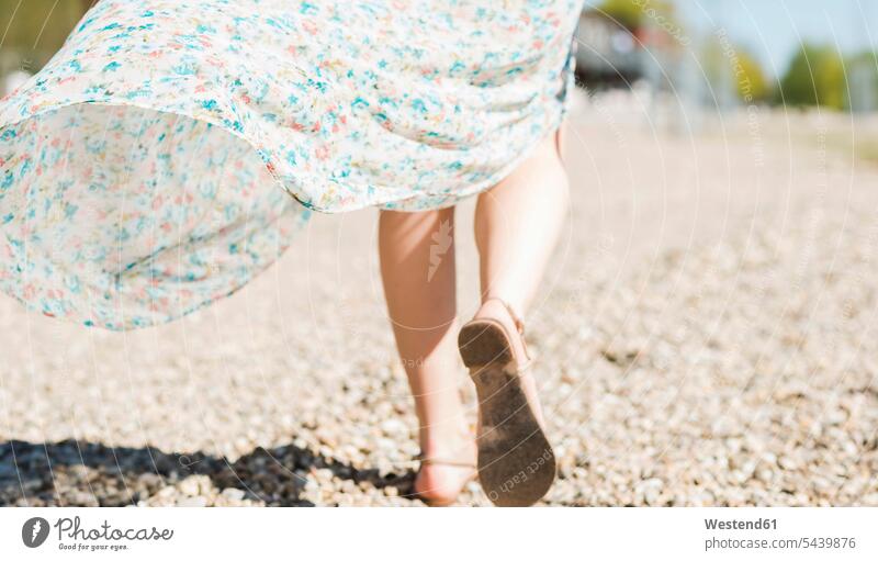 Frau geht am Kiesstrand spazieren gehen gehend Unterer Ausschnitt Sandale Sandaletten Sandalen Anschnitt Teil von Detail Teilabschnitt Teilansicht Kieselstrand