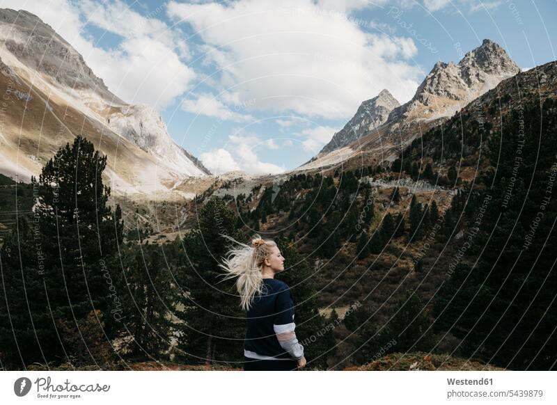 Schweiz, Graubünden, Albulapass, junge Frau mit windzerzaustem Haar in Berglandschaft stehend weiblich Frauen Berge steht Haare Wind Windstoß windig Gebirge