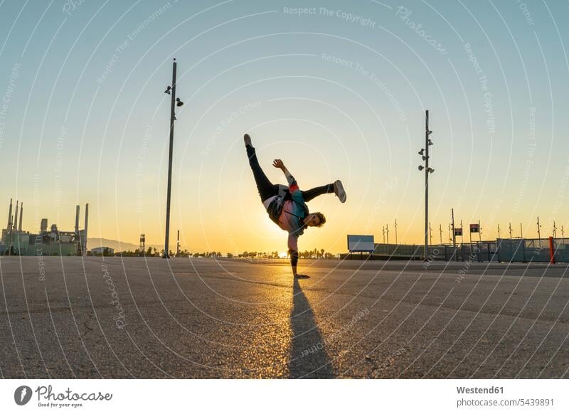 Acrobat macht Handstand in der Stadt bei Sonnenaufgang auf einem Arm Akrobat Akrobaten Handstaende Handstände Sonnenaufgänge Sportler Stimmung stimmungsvoll