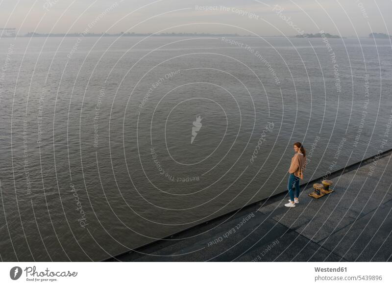Deutschland, Hamburg, Draufsicht auf eine Frau, die auf einem Pier am Elbufer steht stehen stehend Flussufer Landungssteg Piers weiblich Frauen Ufer Erwachsener