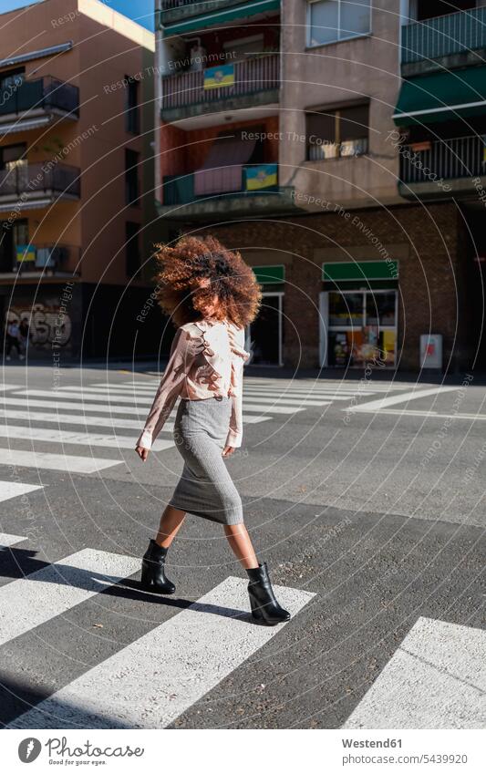 Junge Frau mit Afrofrisur beim Überqueren der Straße in der Stadt Strassen Straßen überqueren Barcelona Gesicht verdeckt verdecktes Gesicht
