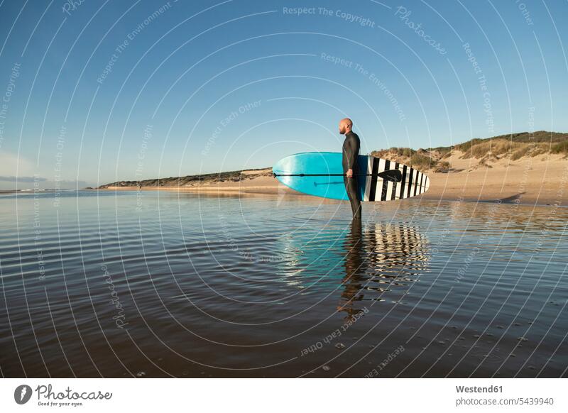 Spanien, Andalusien, Tarifa, Mann hält Stand Up Paddle Board im Meer Meere halten Paddleboard Paddelbrett Männer männlich Gewässer Wasser Erwachsener erwachsen
