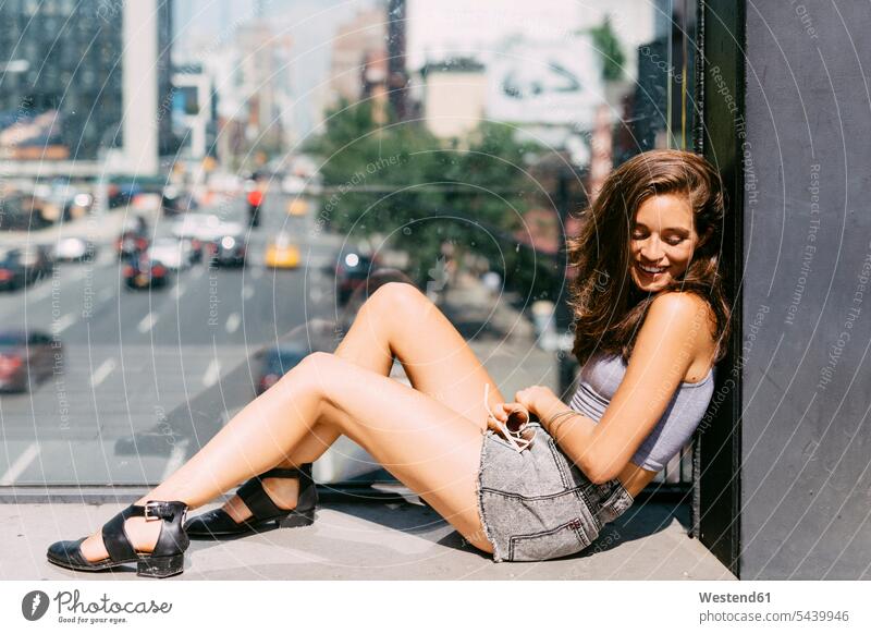 USA, New York City, lächelnde junge Frau entspannt sich in der Stadt Glasscheibe Glasscheiben wegsehen wegschauen Entspannung relaxen Entspannen entspannen