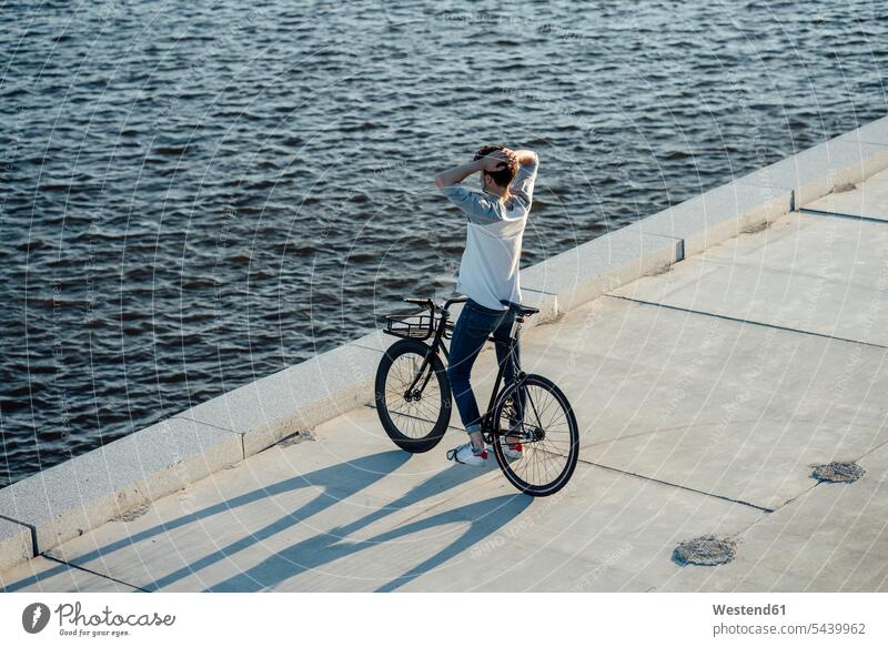 Junger Mann mit Pendler Fixie Fahrrad eine Pause am Flussufer haben Pause machen Männer männlich Fluesse Fluß Flüsse Bikes Fahrräder Räder Rad Erwachsener