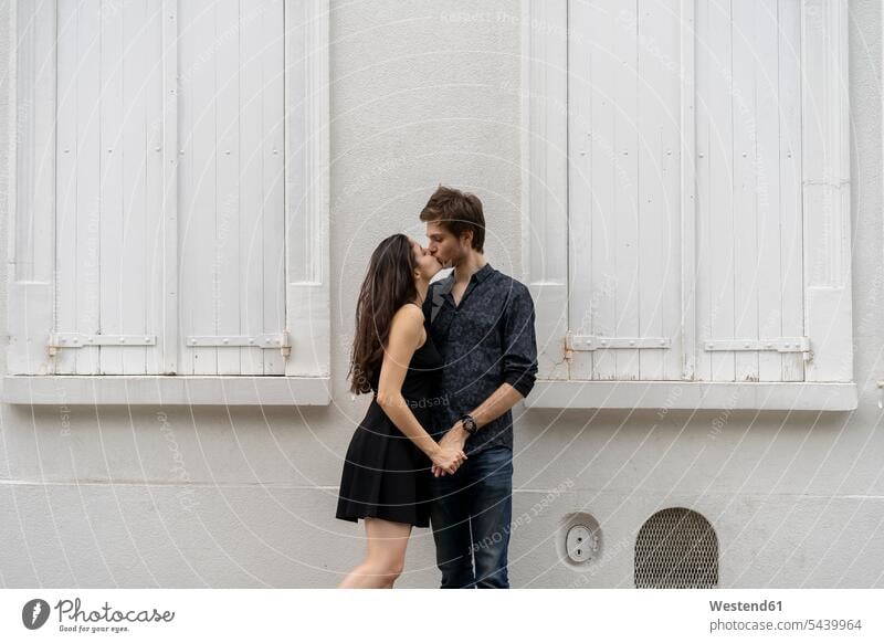 Junges verliebtes Paar küsst sich vor dem Gebäude küssen Küsse Kuss Pärchen Paare Partnerschaft Mensch Menschen Leute People Personen Bauwerk Bauwerke Europäer