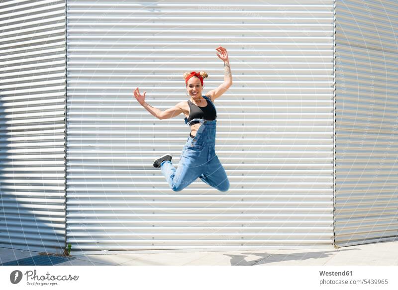 Lächelnde junge Frau springt in die Luft Luftsprung Luftsprünge einen Luftsprung machen Luftspruenge weiblich Frauen springen hüpfen Sprung Spruenge Sprünge