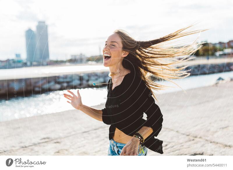 Überschwängliche junge Frau an der Strandpromenade ausgelassen Ausgelassenheit lachen weiblich Frauen glücklich Glück glücklich sein glücklichsein positiv