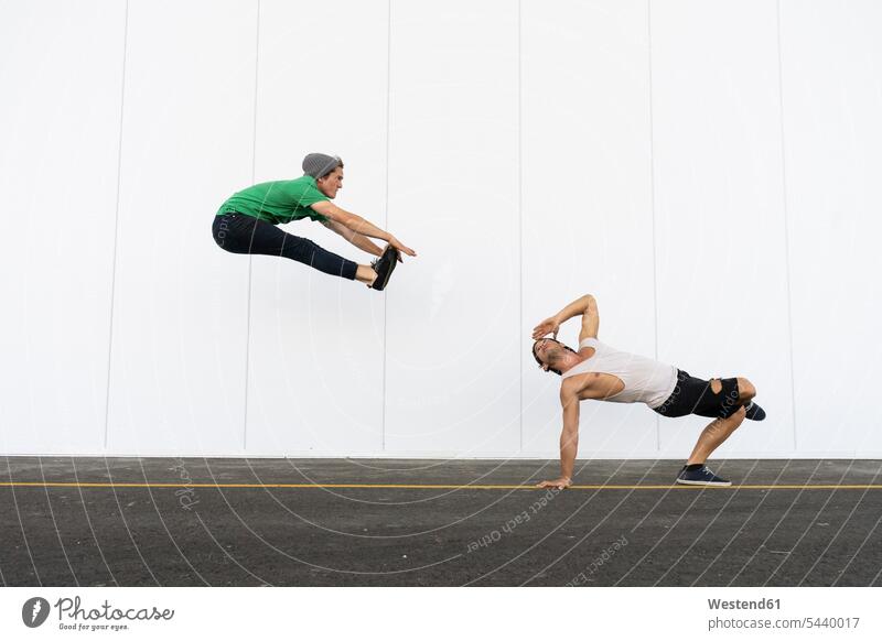 Zwei Akrobaten machen gemeinsam Kunststücke, springen in der Luft Trainieren Sprung anders Spaß Freiheit unkonventionell Nonkonformität weiß Körperbeherrschung