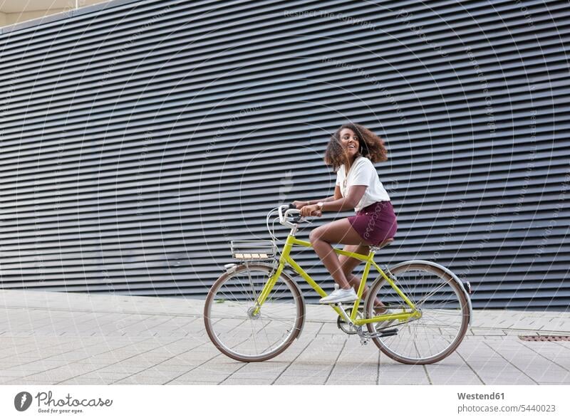 Lächelnde junge Frau beim Fahrradfahren fahrradfahren radeln Bikes Fahrräder Räder Rad lächeln weiblich Frauen Raeder Verkehrswesen Transportwesen Erwachsener