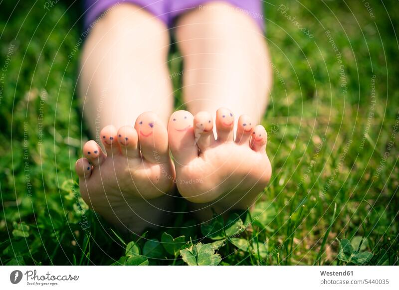 Kleine Mädchenfüsse mit bemalten Zehen im Gras liegend Natur Freizeit Muße Humor spaßig lustig grüner Hintergrund Nahaufnahme Großaufnahme close-ups