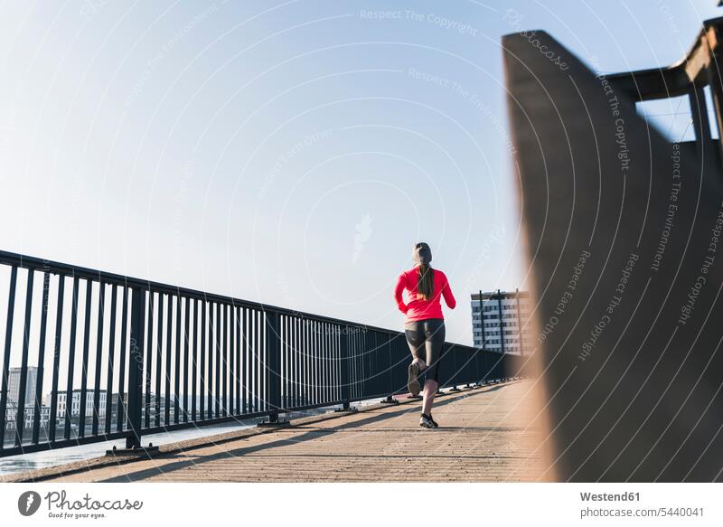 Junge Frau rennt auf der Brücke in der Stadt Joggen Jogging staedtisch städtisch weiblich Frauen laufen rennen Bruecken Brücken Fitness fit Gesundheit gesund