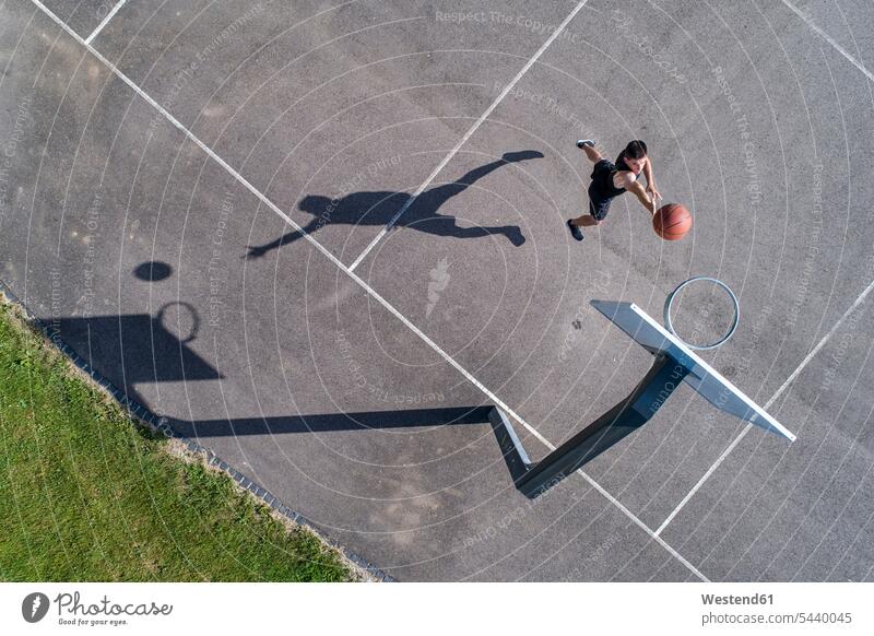 Luftaufnahme eines jungen Mannes beim Basketball spielen werfen Wurf dunking Basketballkorb Basketballkoerbe Basketballkörbe Sport Korb werfen Luftsprung