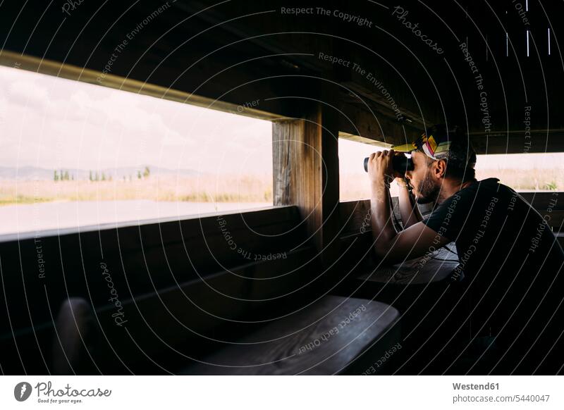 Mann bei der Vogelbeobachtung mit Fernglas von einem Aussichtsturm Hochsitz Hochsitze Hochstand Männer männlich beobachten zuschauen ansehen erkunden