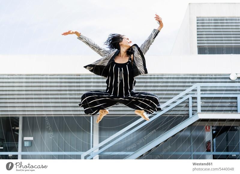 Balletttänzerin, die mit einem Smartphone springt und ein Selfie vor einem Bürogebäude macht Balletttaenzerinnen Ballerina Ballerinas Balletttänzerinnen