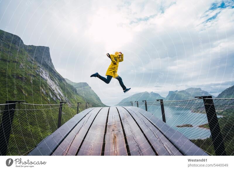 Norwegen, Insel Senja, Mann springt auf eine Aussichtsplattform an der Küste Kueste Kuesten Küsten Männer männlich springen hüpfen Erwachsener erwachsen Mensch