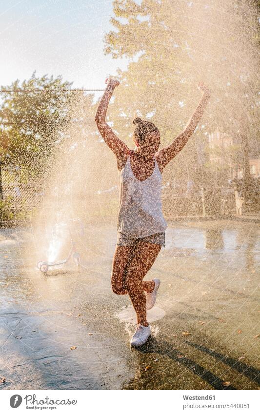 Junge Frau springt Wasserstrahl eines Springbrunnens weiblich Frauen attraktiv schoen gut aussehend schön Attraktivität gutaussehend hübsch Wasserspritzer