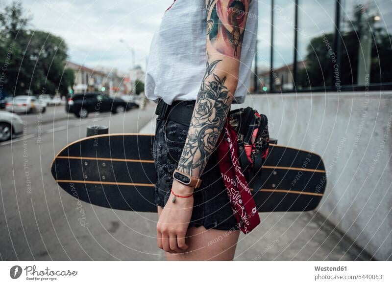 Nahaufnahme einer jungen Frau, die ein Skateboard auf dem Bürgersteig hält Rollbretter Skateboards halten weiblich Frauen Gehsteig Gehwege Gehsteige
