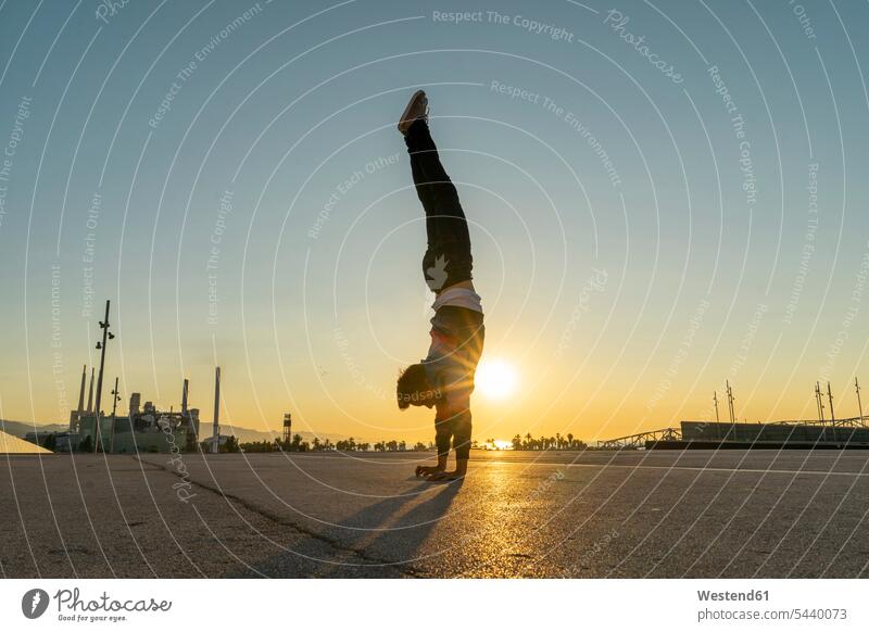 Acrobat macht Handstand in der Stadt bei Sonnenaufgang Handstaende Handstände Akrobat Akrobaten Sonnenaufgänge Sportler Stimmung stimmungsvoll Atmosphäre