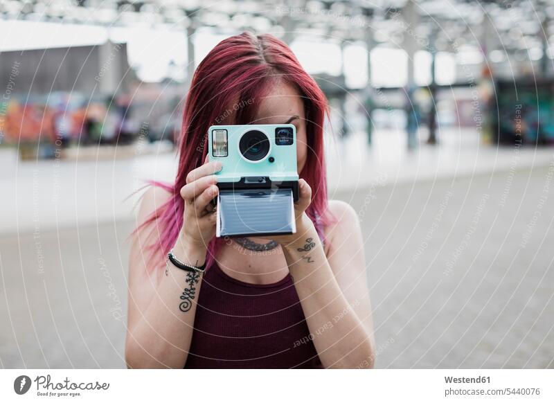 Junge Frau beim Fotografieren mit Sofortbildkamera im Freien weiblich Frauen Polaroids Sofortbilder Fotoapparat Kamera Fotokamera fotografieren Erwachsener